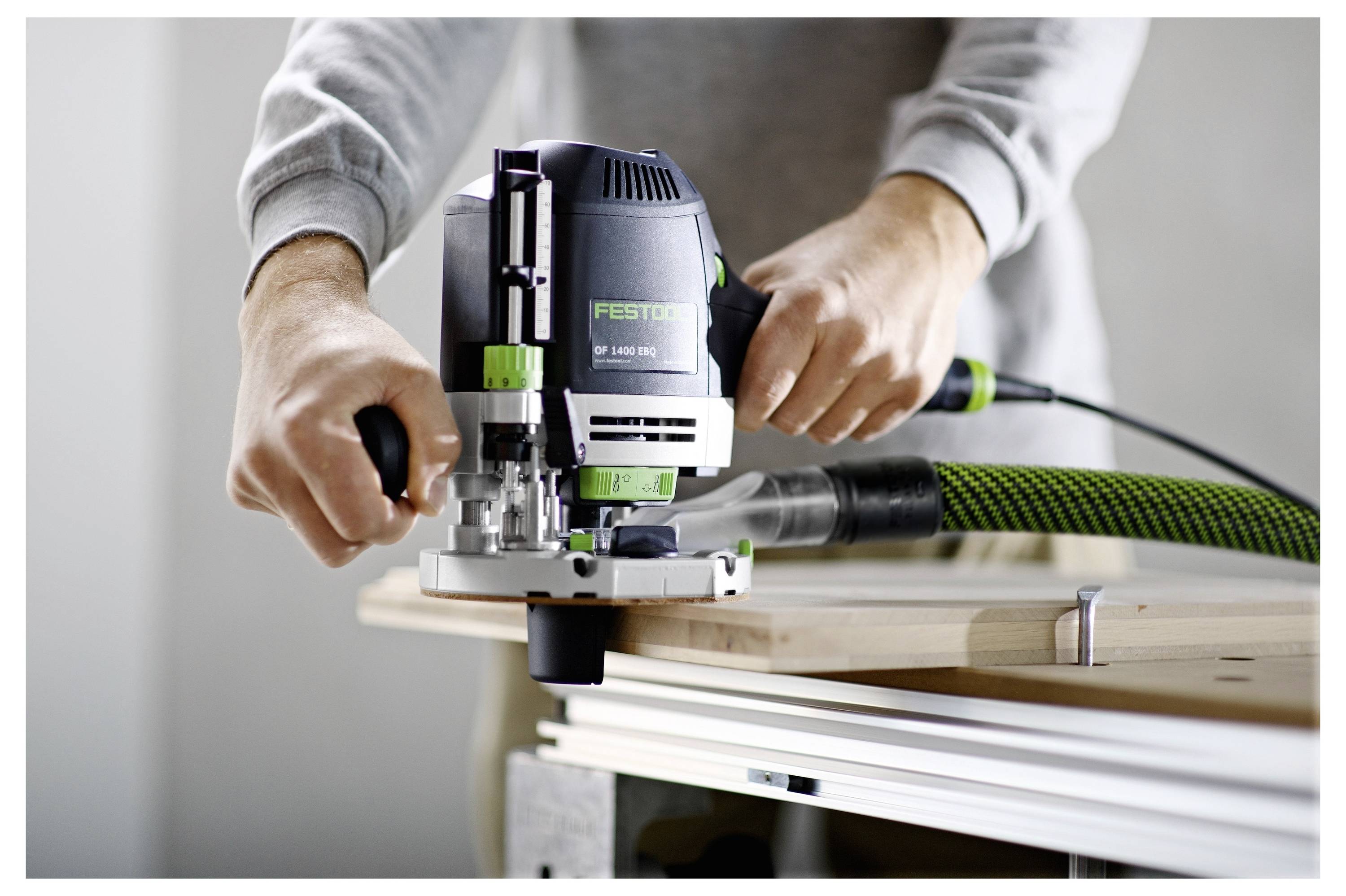 A person using a power router on a wooden board, focusing on precise control and smooth edges.
