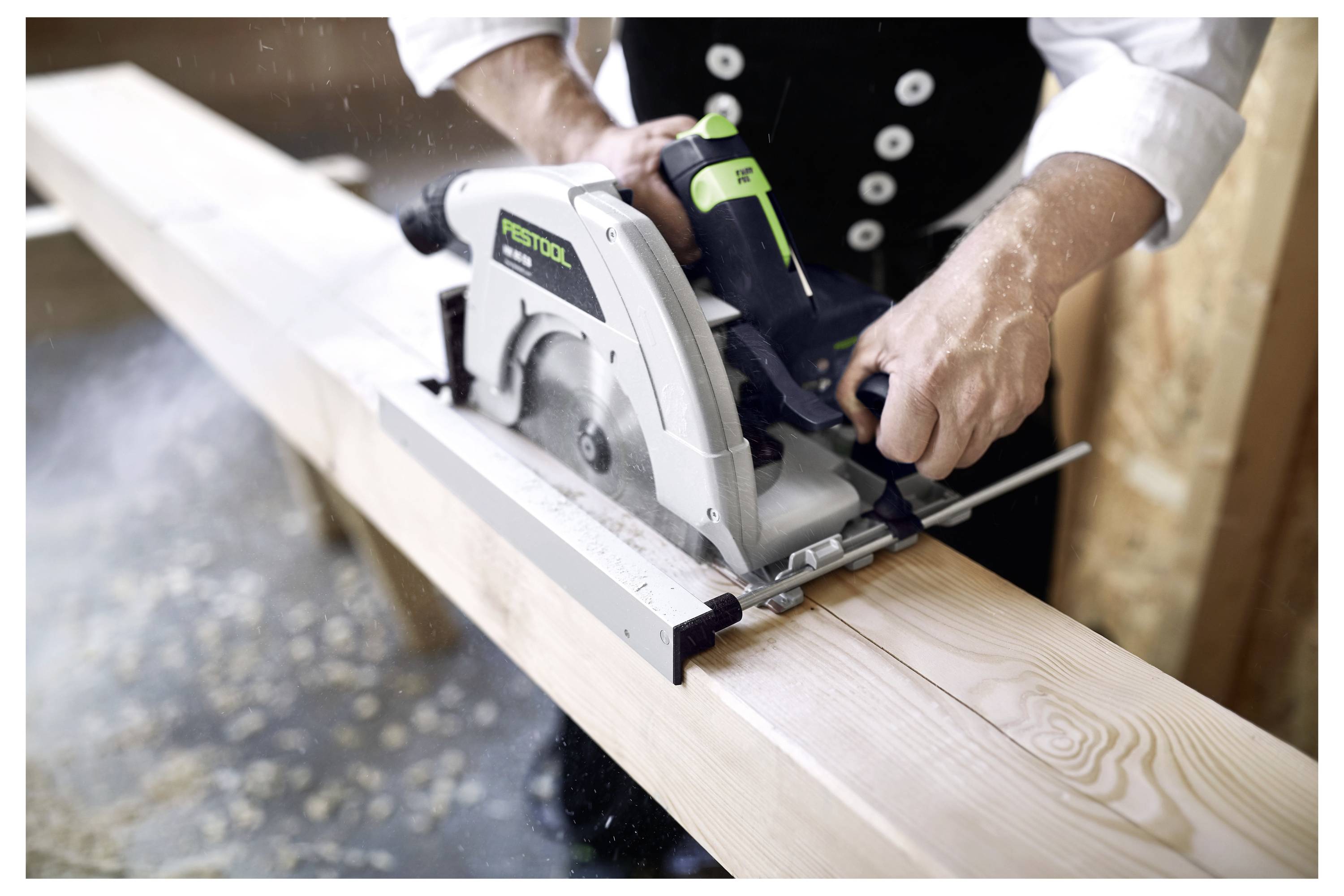 A person uses a power saw to cut a wooden beam, focusing on accuracy and precision. Dust particles are visible in the air.
