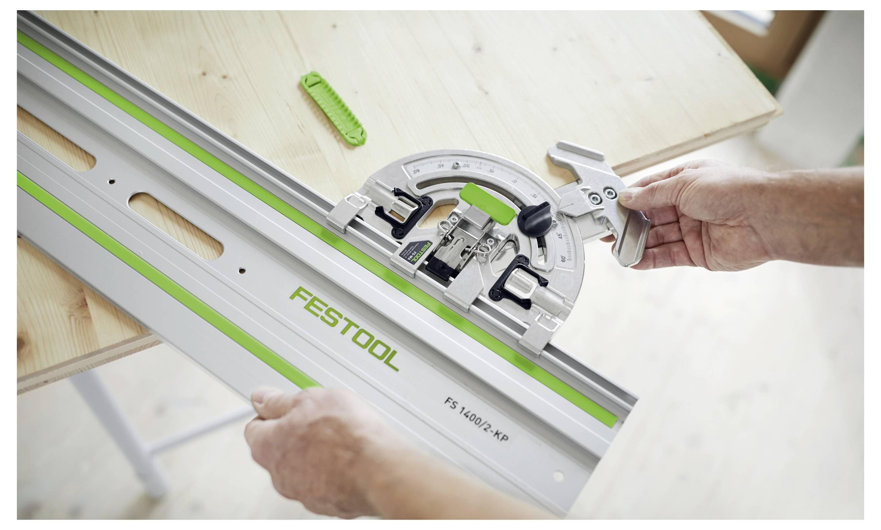 A person adjusts a Festool circular saw guide on a wooden table, demonstrating its use for precise angle cutting.
