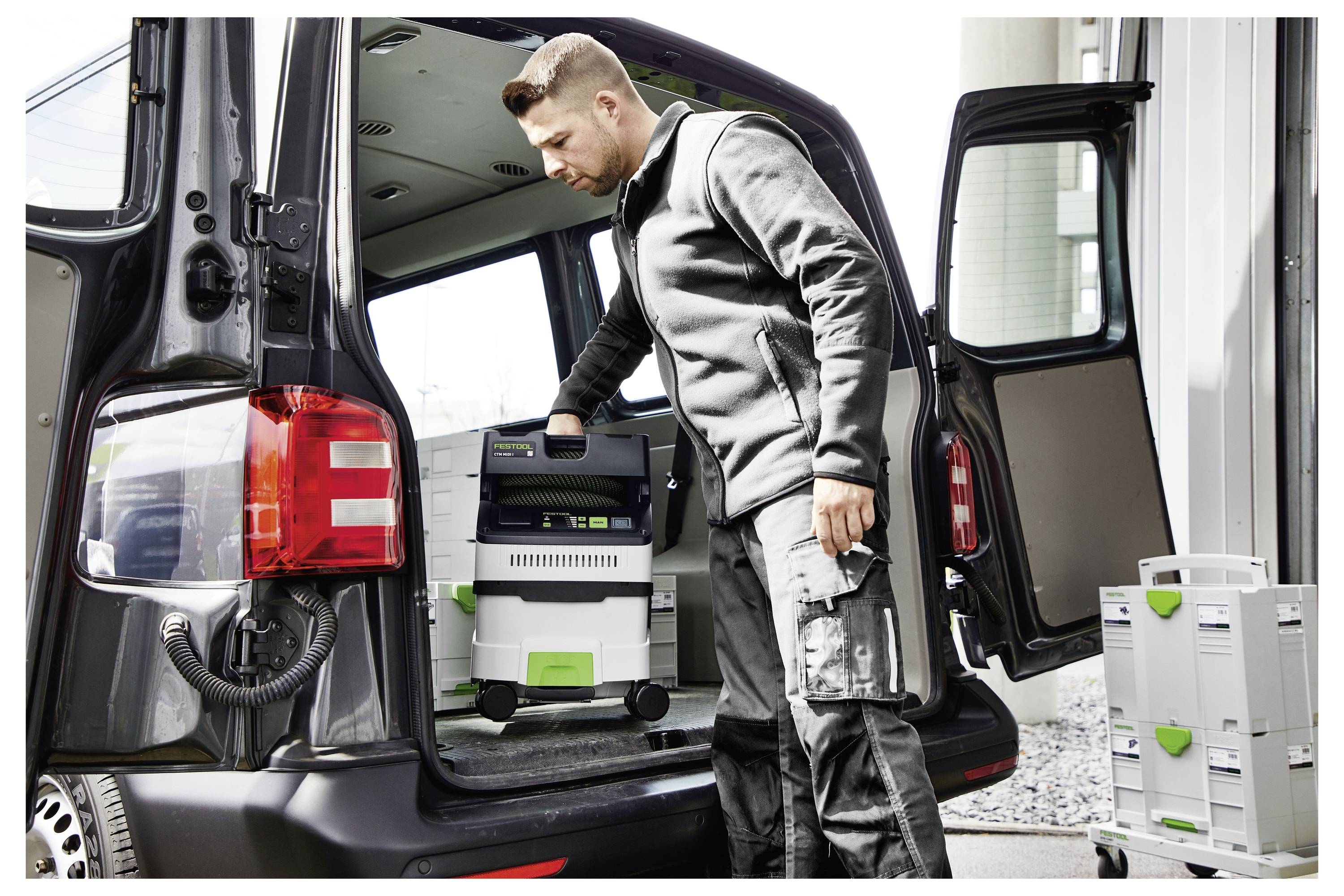 A man loads portable storage boxes into a black van, suggesting a focus on mobility and organization in a professional context.