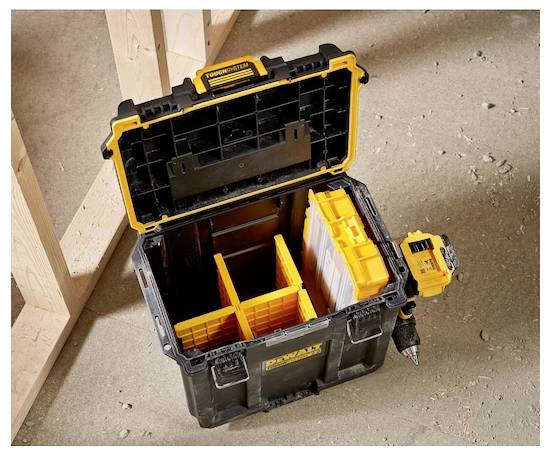 A black and yellow tool box with open compartments is sitting on a concrete floor, next to a cordless drill, in a construction area.