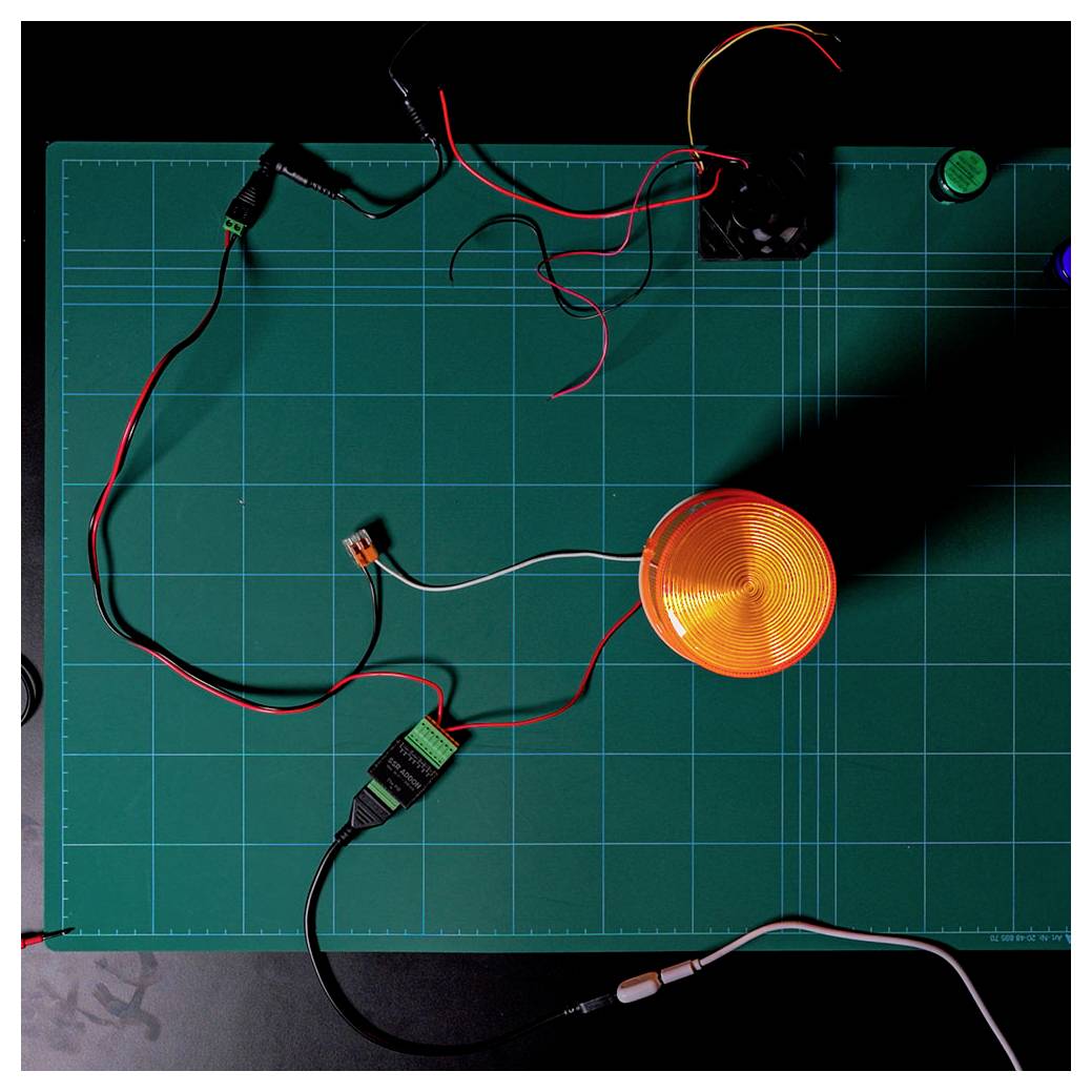 A green cutting mat with an orange coil, black and red wires, and connectors spread across, suggesting an electronics work in progress.