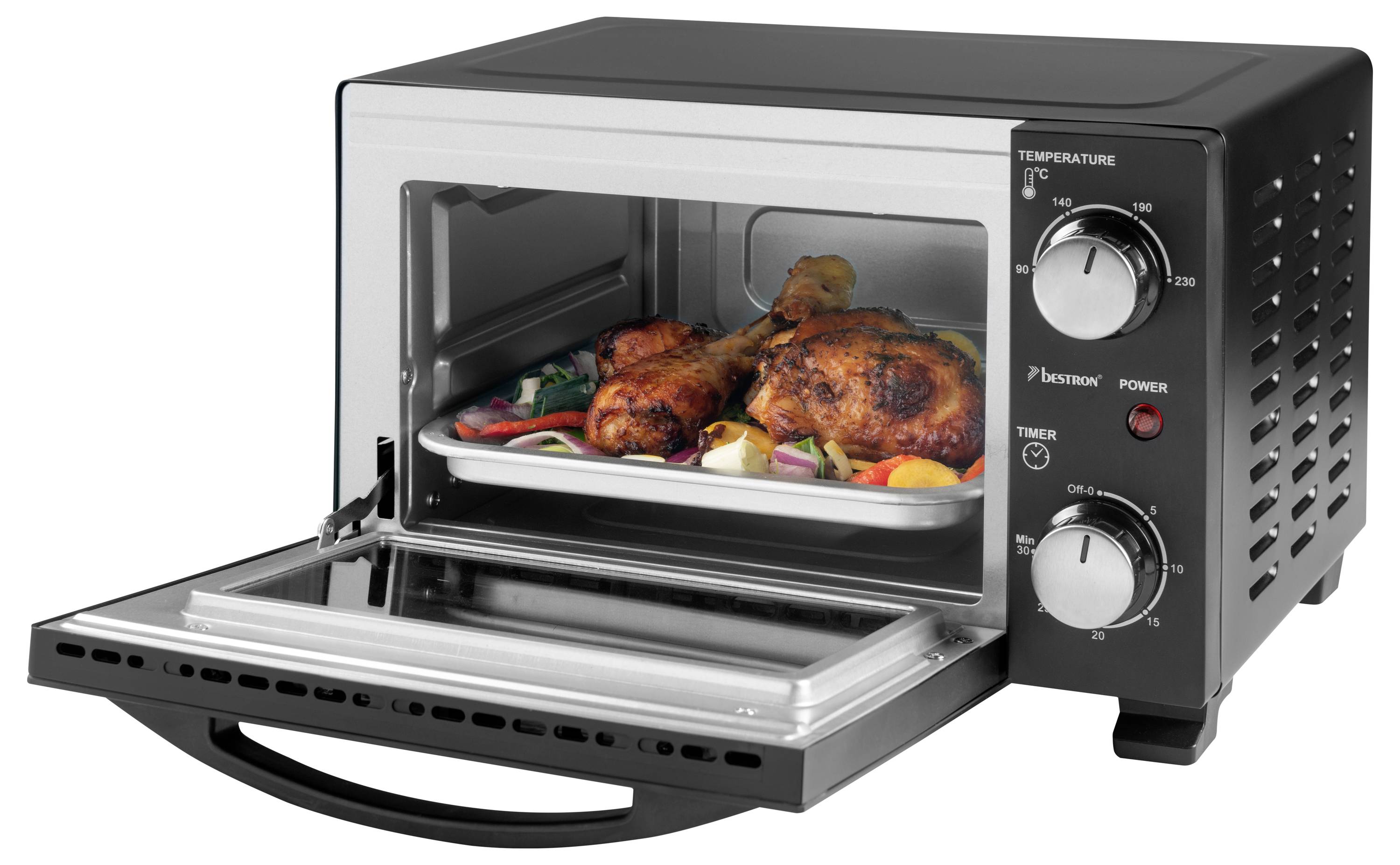 A toaster oven with an open door reveals roast chicken legs and vegetables on a tray, with temperature and timer dials on the right.