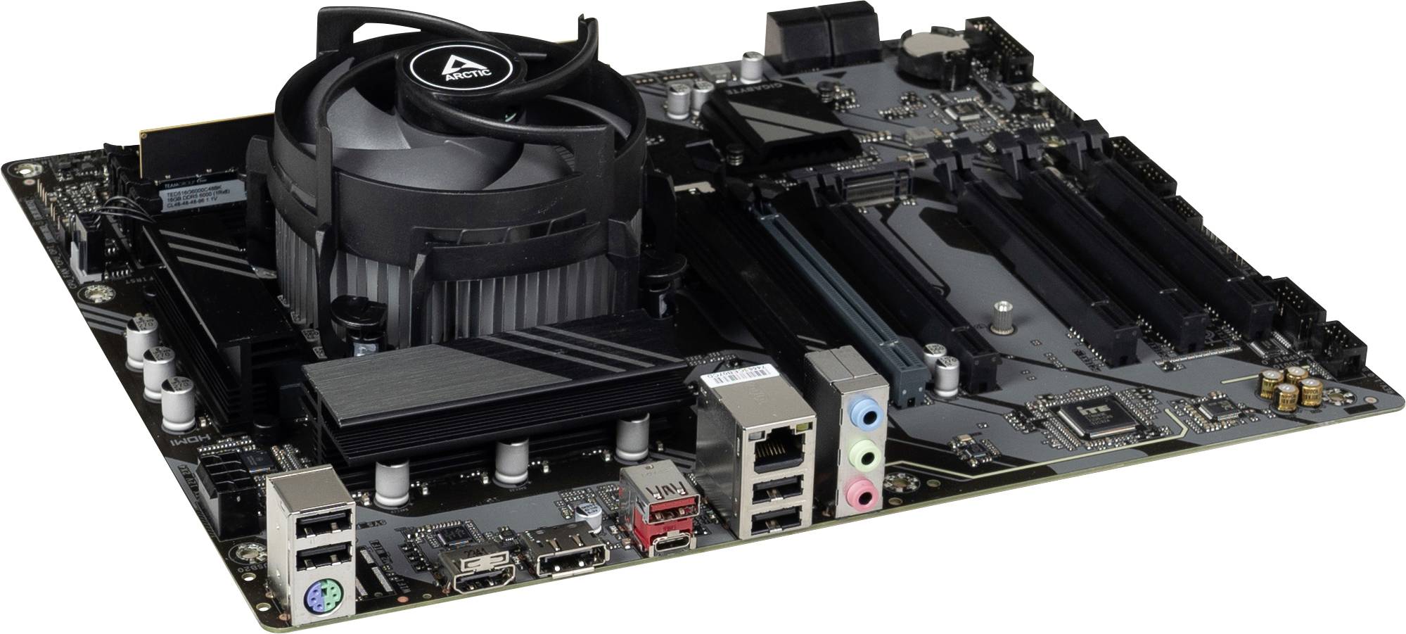 Desktop computer motherboard with installed CPU cooling fan and heatsink, showing rear ports and expansion slots on a white background.