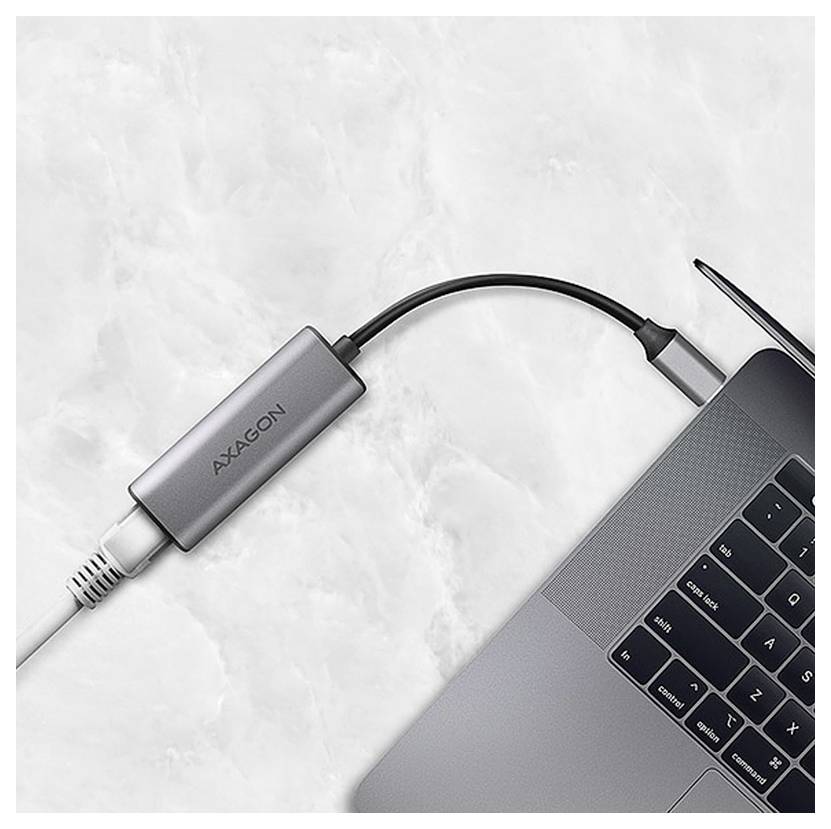 Laptop connected to a white cable via a gray AXAGON adapter on a marble surface.