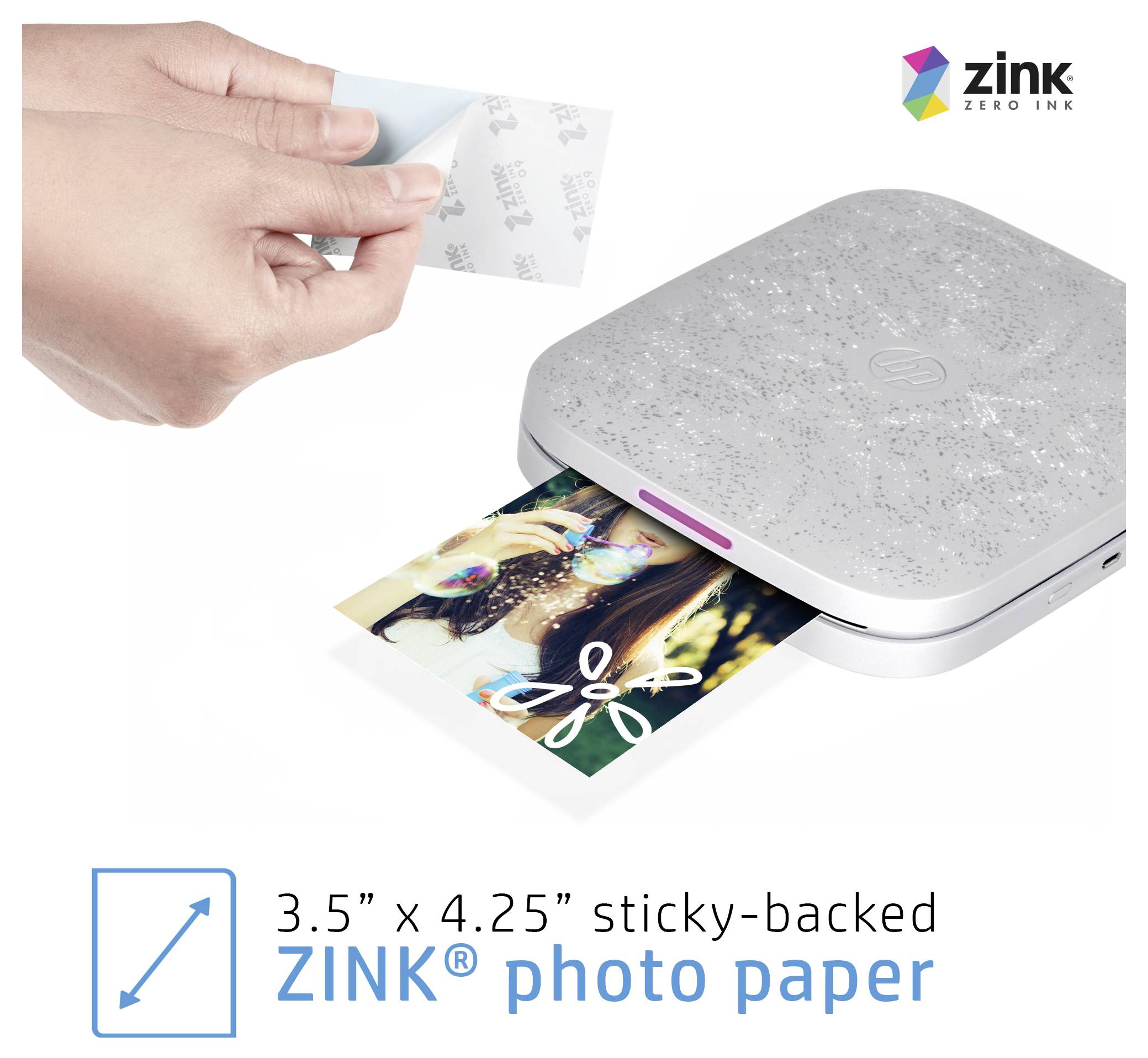 Hand peels back sticky backing from ZINK photo paper being printed from a compact photo printer; text says 3.5 x 4.25 sticky-backed ZINK photo paper.
