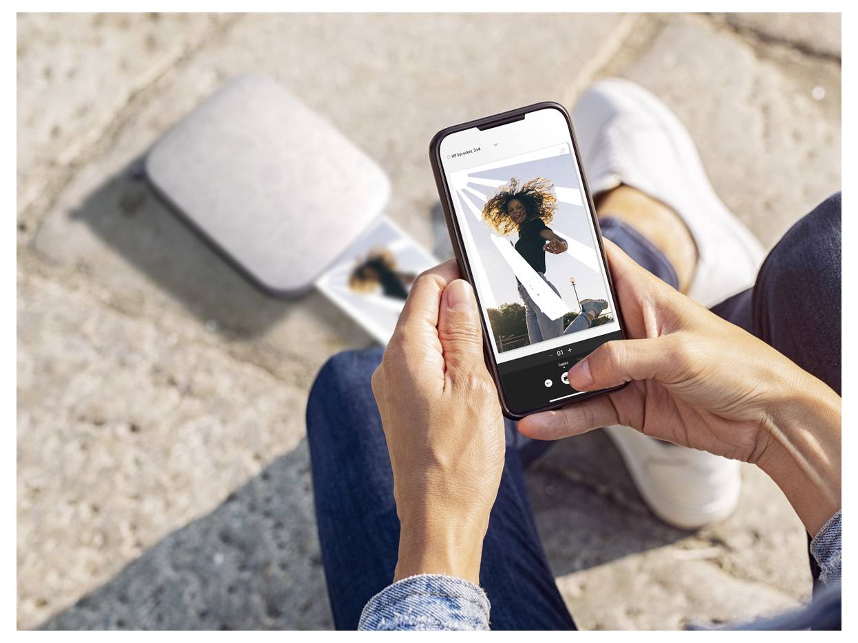 Person holding a smartphone and viewing a photo of a woman posing outdoors while sitting on steps in sunlight