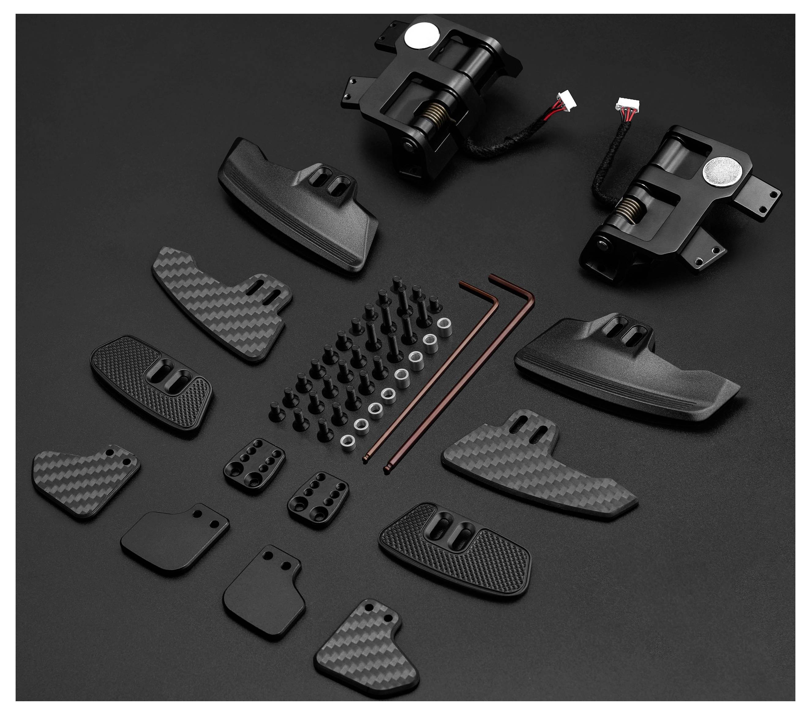 Assorted black carbon-fiber and plastic automotive parts laid out on a dark surface, including brackets, covers, screws, clips, and hex keys.