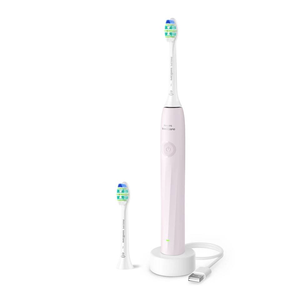 Pink electric toothbrush with charging base, USB cable, and two brush heads on a white background.