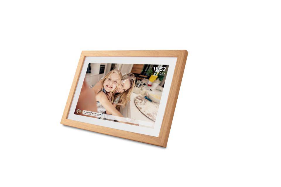 Wooden digital photo frame displaying a smiling woman and child at a table, with the time 10:53 shown in the corner.