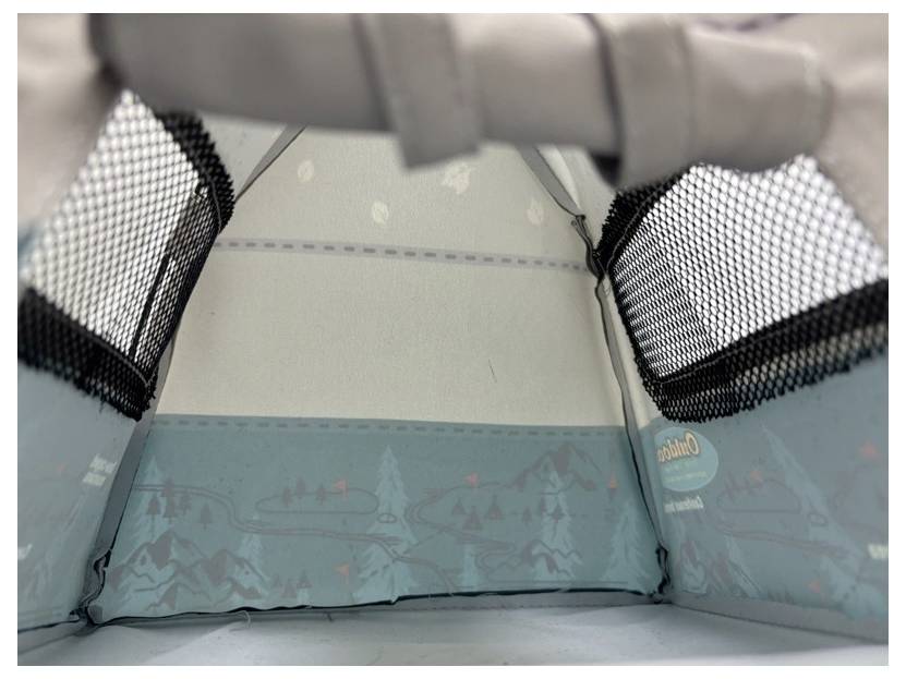 Inside a small blue children’s play tent with mesh side windows and mountain-themed panels, viewed from inside looking out.
