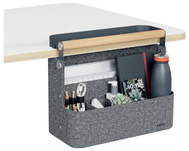 Hanging felt desk organizer with compartments holding pens, cables, notebook, plant, sanitizer, and water bottle on a tabletop.