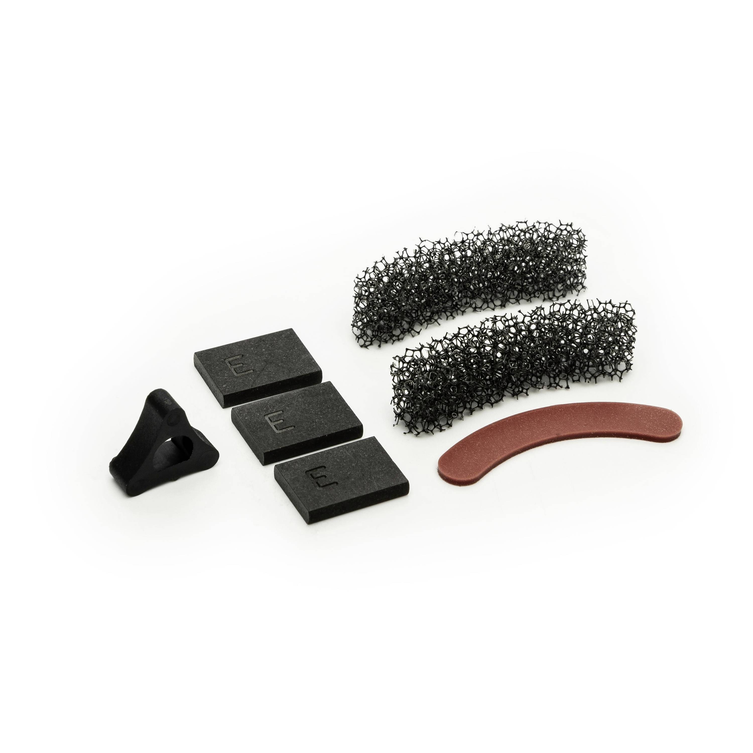 Assorted small black foam and mesh filter parts with one curved red strip on a white background.