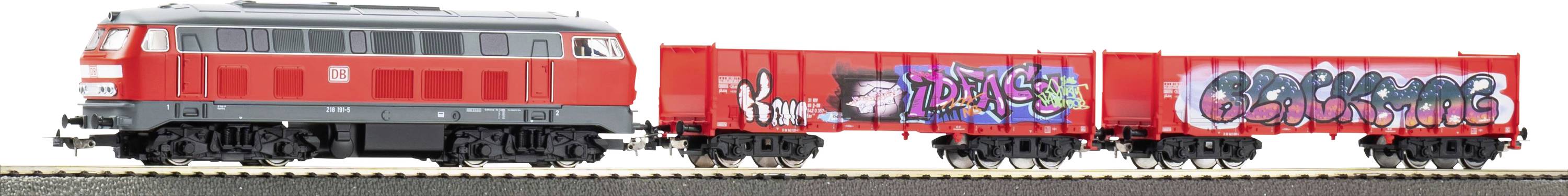 A red and gray locomotive train moves along a track, covered in colorful graffiti on the side.