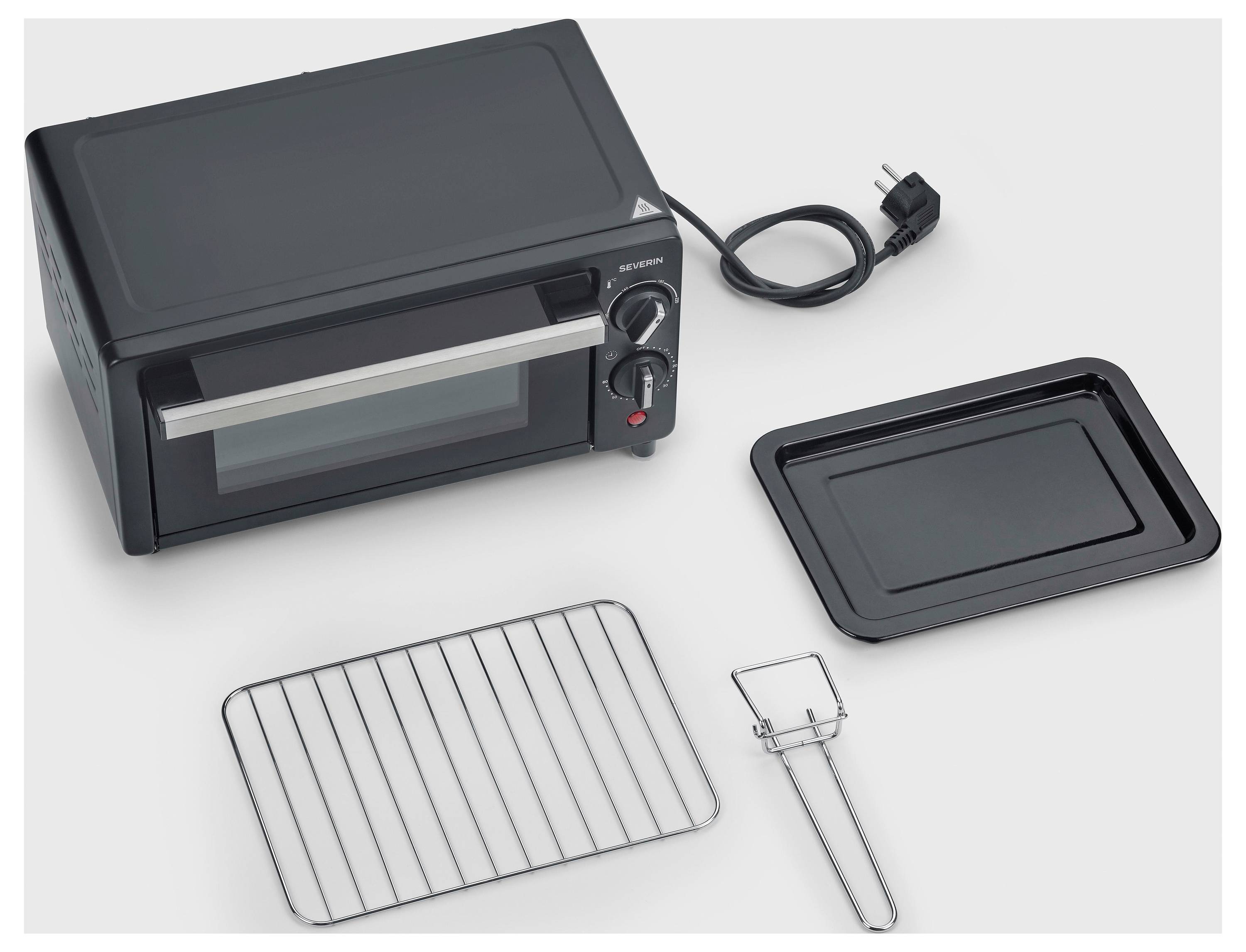 Countertop toaster oven with wire rack, baking tray, crumb tray, and tongs/handle accessory on a white surface.