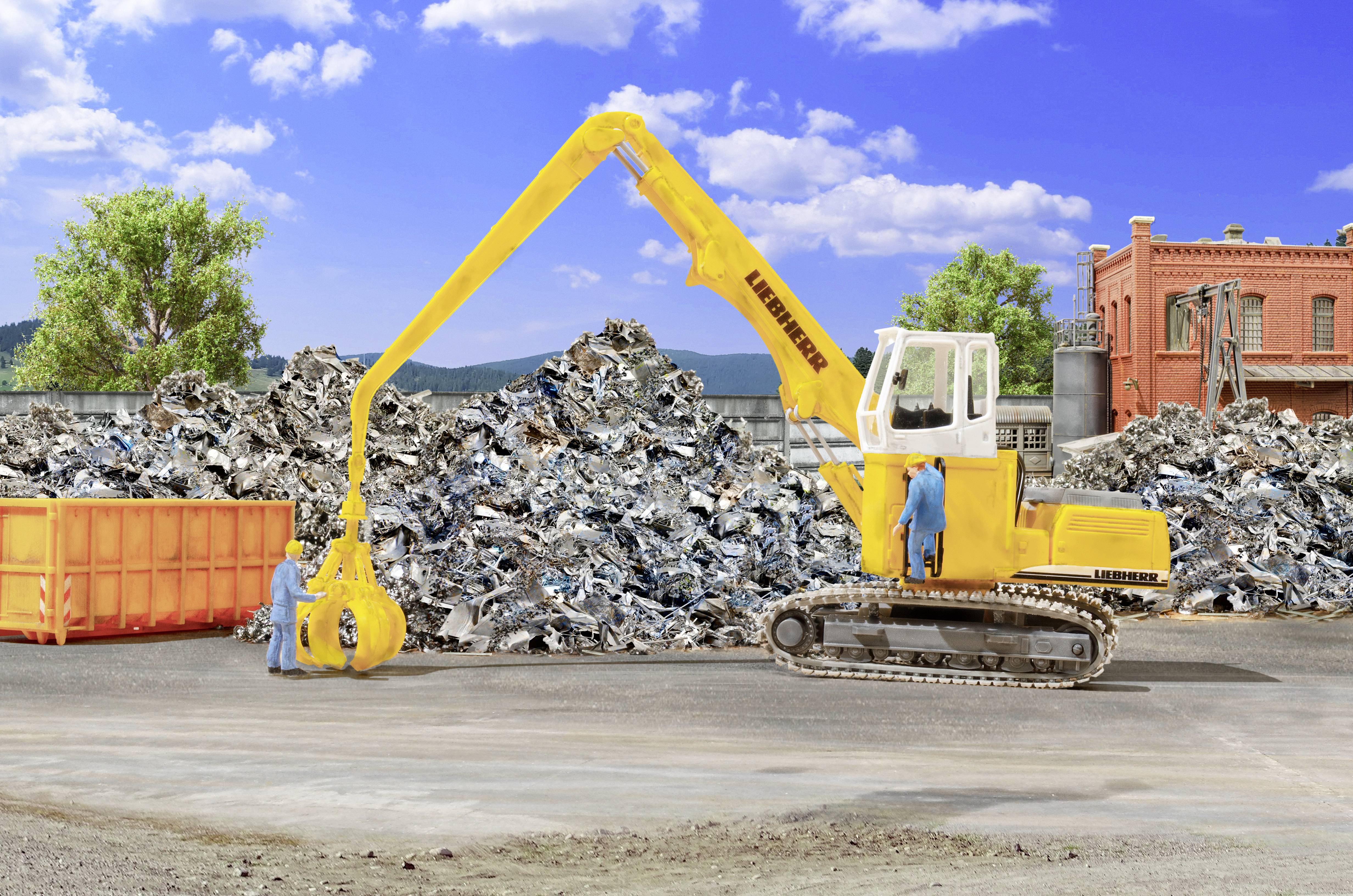 Yellow excavator with grapple sorting scrap metal in a junkyard, with workers nearby and piles of recycled debris