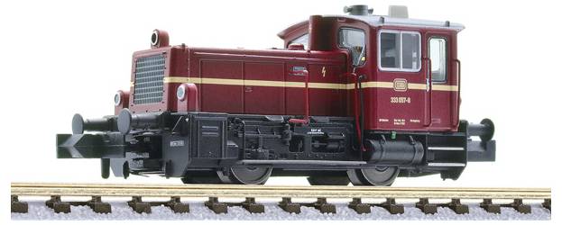 Red model locomotive on railroad tracks, shown in side view on a white background.