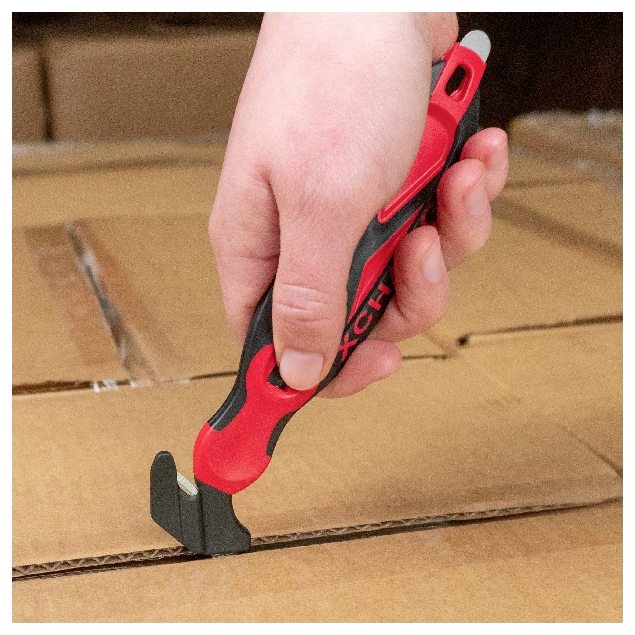 Hand using a red and black box cutter to slice open a cardboard shipping box.