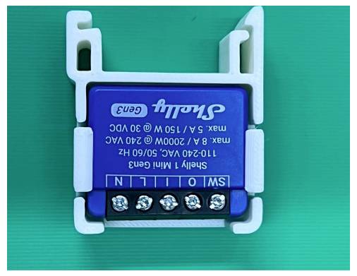 Blue Shelly 1 Mini Gen3 smart relay module with screw terminals, shown on a green background; label lists 110-240V AC and max 5A/2400W.