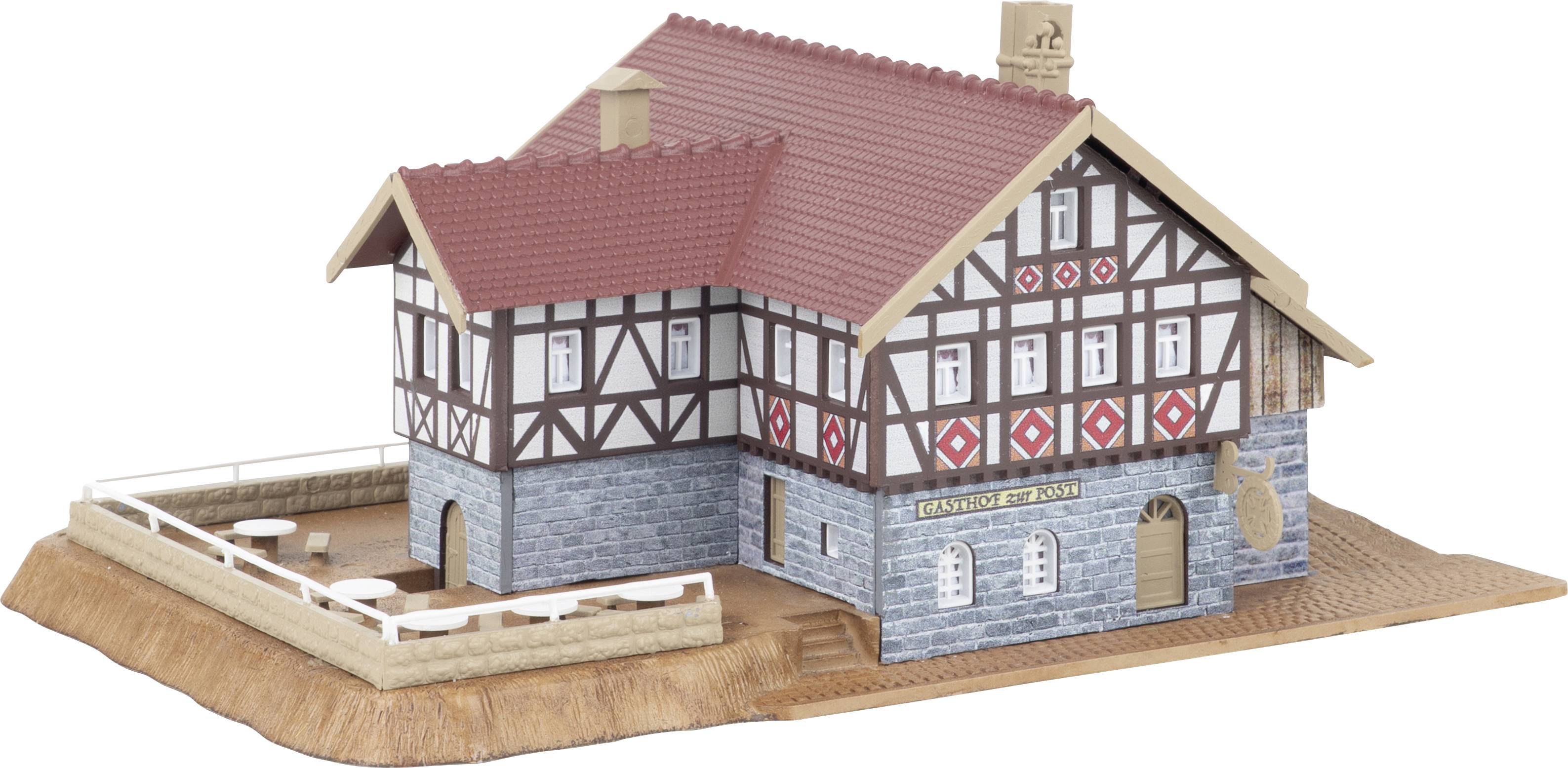 Model of a half-timbered house with red roof and stone base, shown on a display platform.