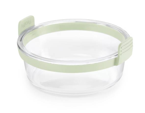 Clear round glass food container with a pale green silicone lid and side tabs, shown isolated on a white background.