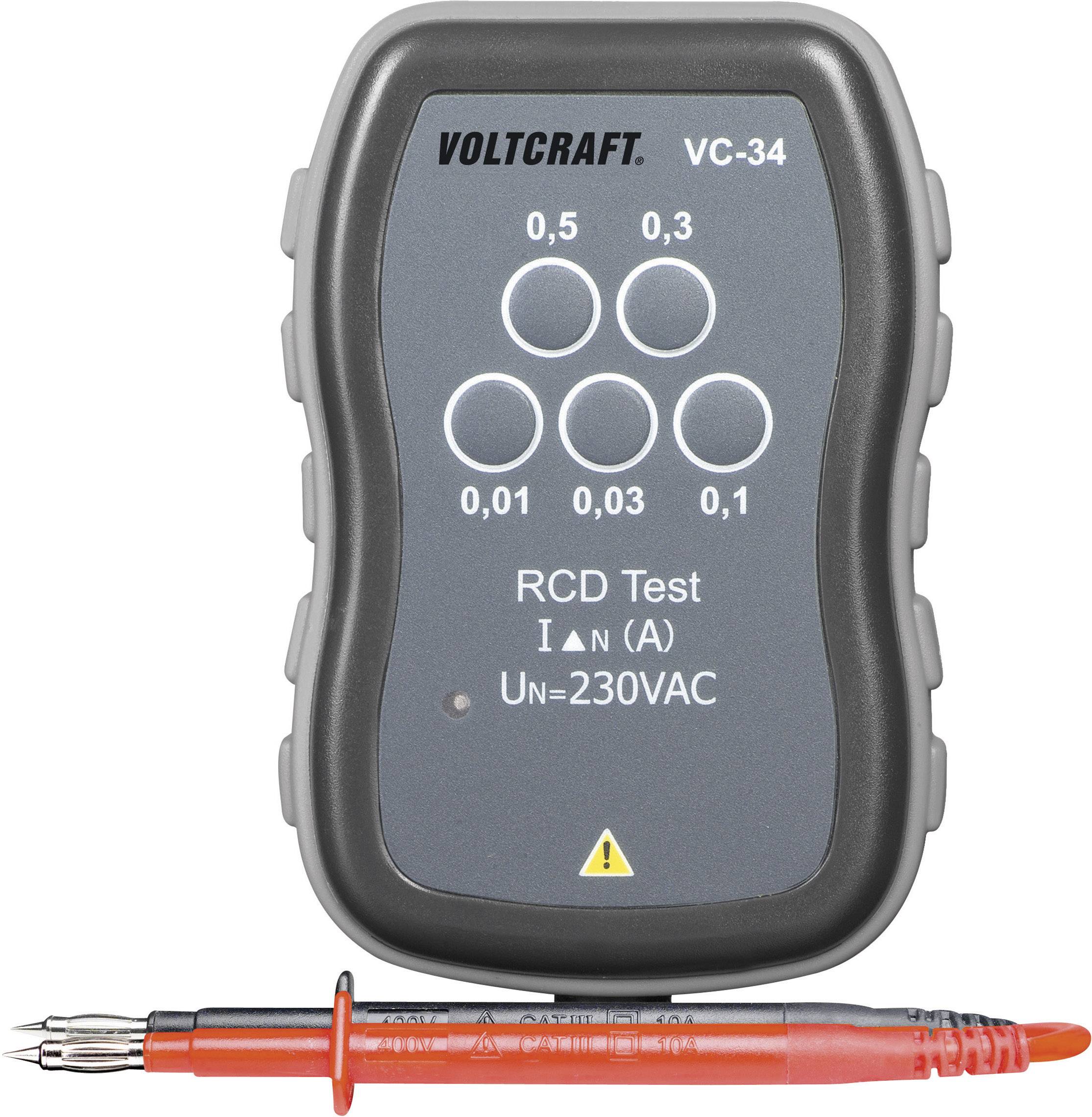 A residual current device (RCD) tester with the inscription 'VOLTCRAFT VC-34', shows test holes for various current strengths (0.5 A to 0.03 A), voltage 230 VAC. A test probe lies in front of it.