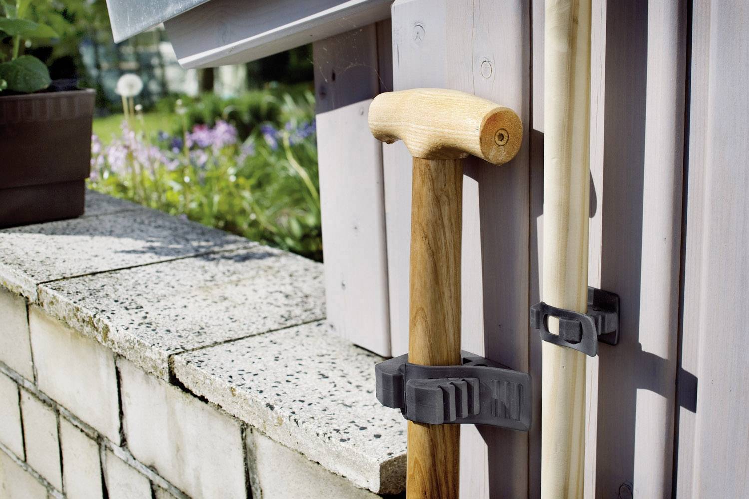 Walking stick and cane are fixed to the house wall in a plastic holder.