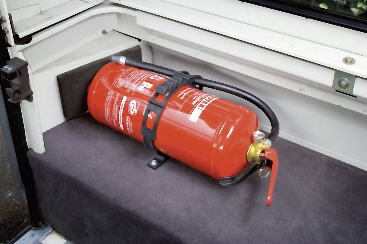 Fire extinguisher in a vehicle, securely fastened in a holder in the boot.