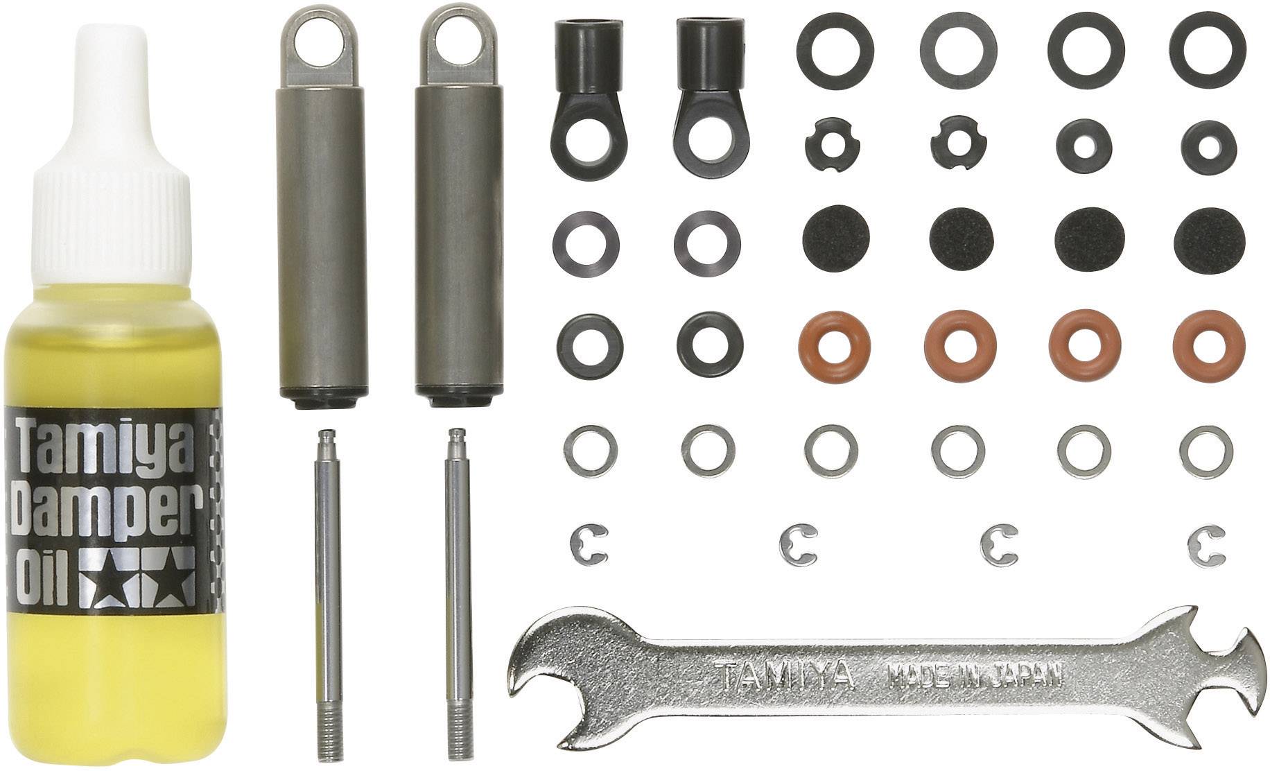 A kit for shock absorbers with a bottle of damper oil, two cylinders, seals, screws, washers, and a spanner.