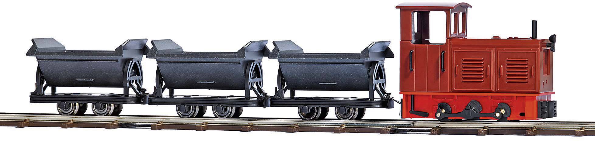 Toy steam locomotive with three black coal wagons on a railway track. Locomotive in red colour, model railway layout.