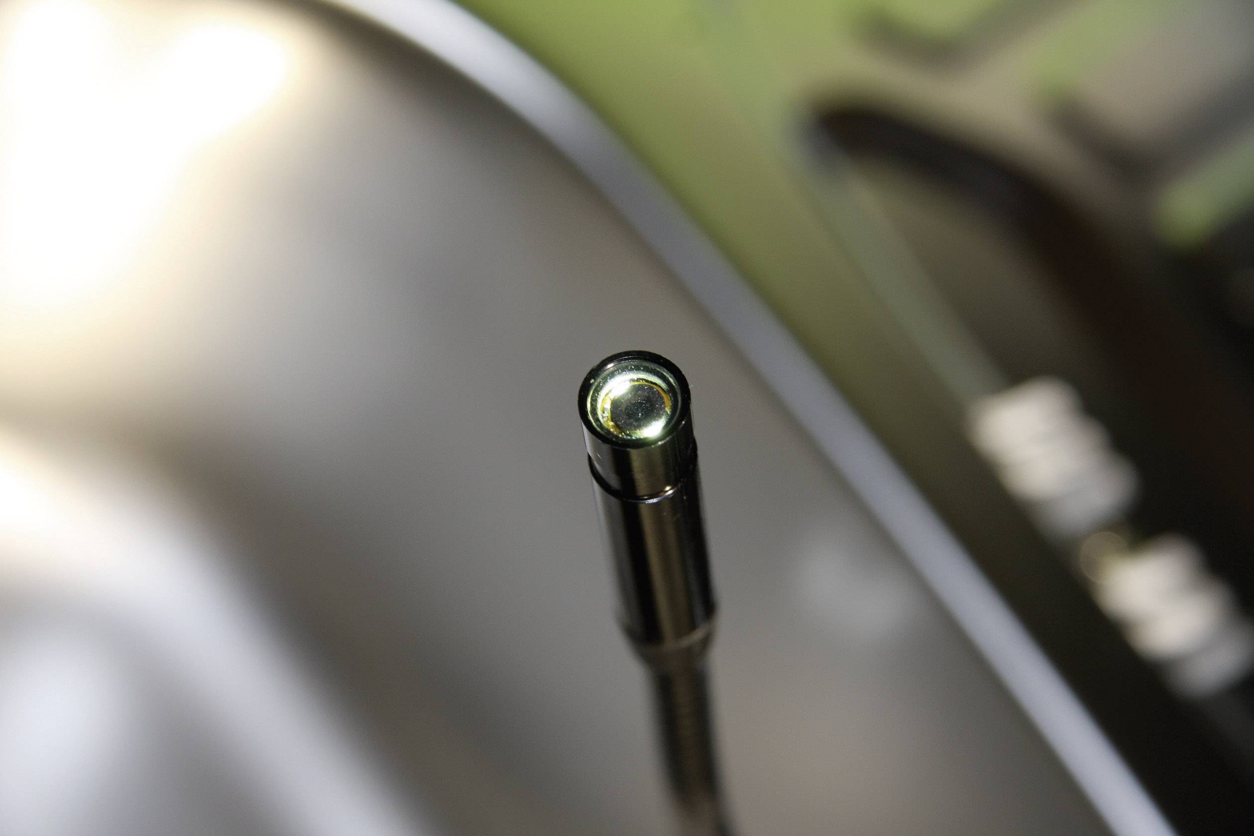 Close-up of a microphone with a focused view of the capsule tip, surrounded by a blurred background.
