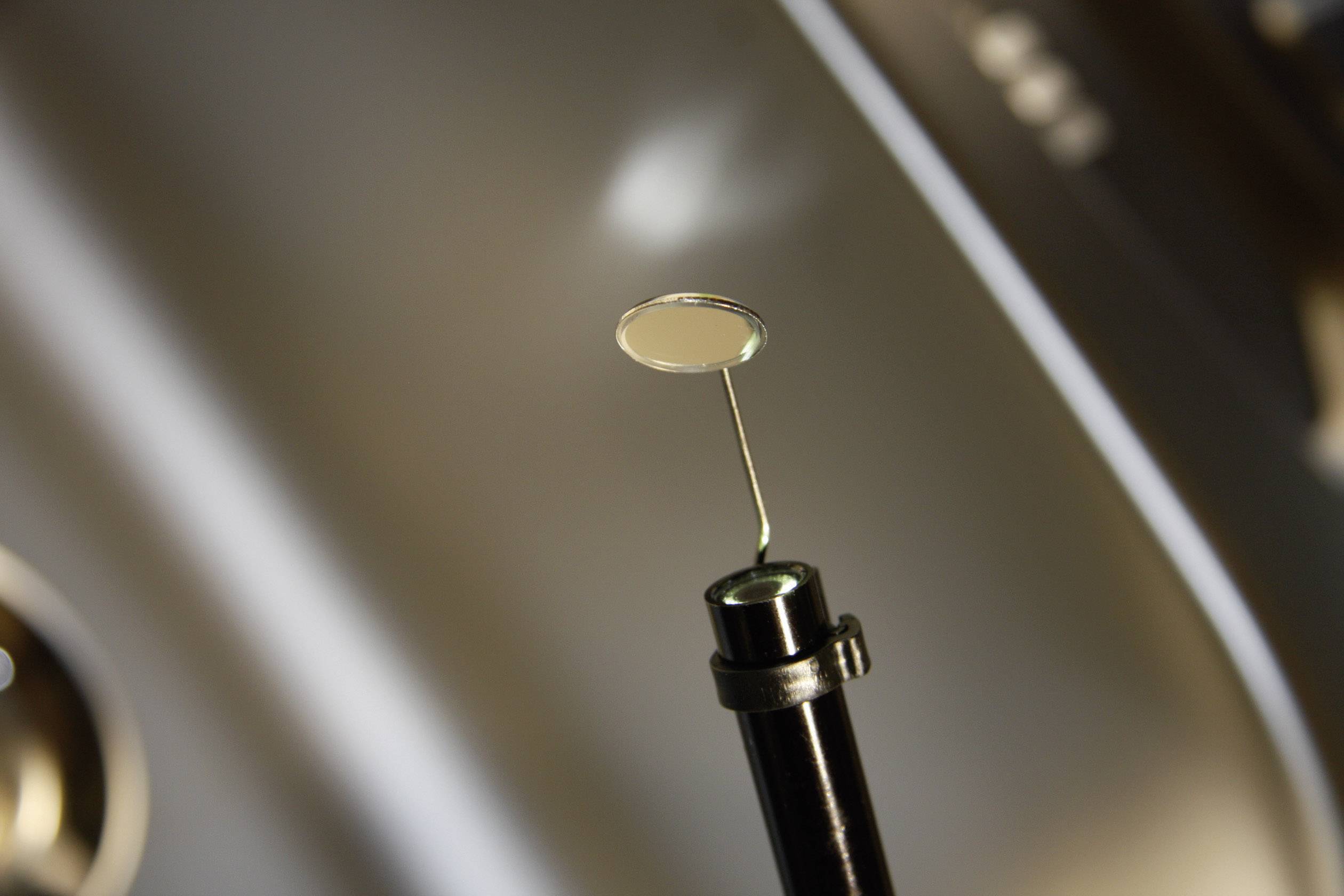 Dental mirror with a metal handle in a dental practice against a blurred background.