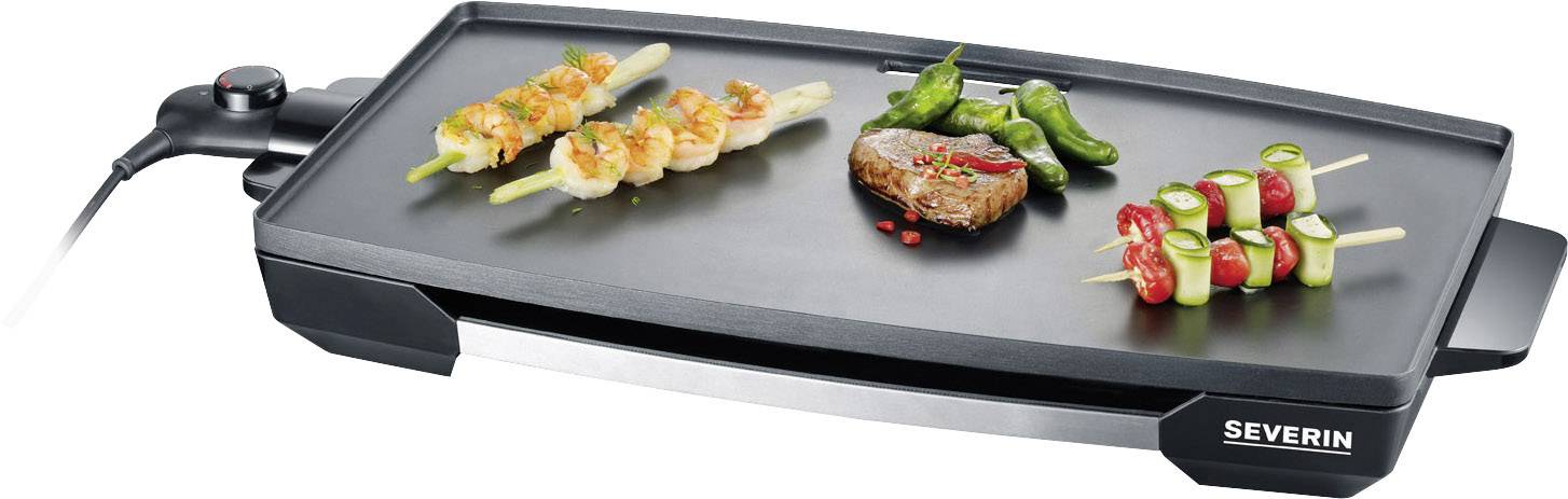 An electric table grill with various foods: chicken skewers, a steak, vegetables and peppers are being grilled on it.