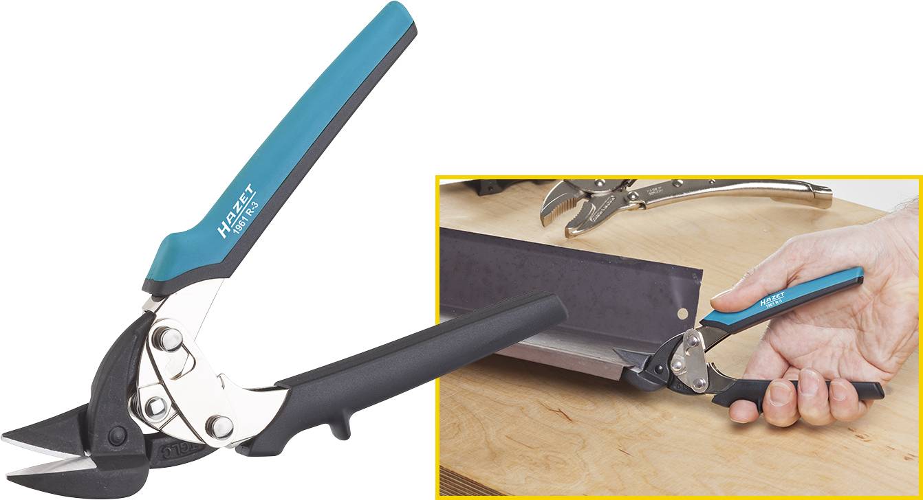 A blue and black metal shears cuts a metal sheet. A hand holds the shears on a wooden table.