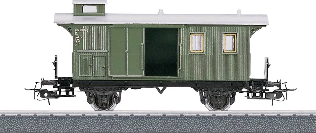 A green model goods wagon of the railway on a track, with small windows and a sliding door, shows rail vehicle details.