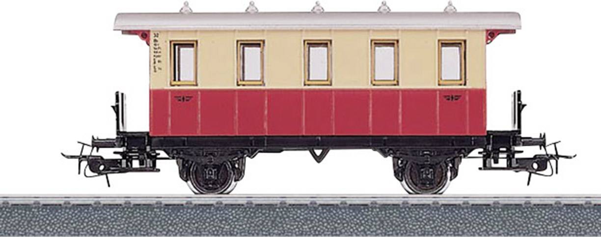 A model of a historical railway carriage in red and beige stands on a track. Detailed wheels and couplings are visible.