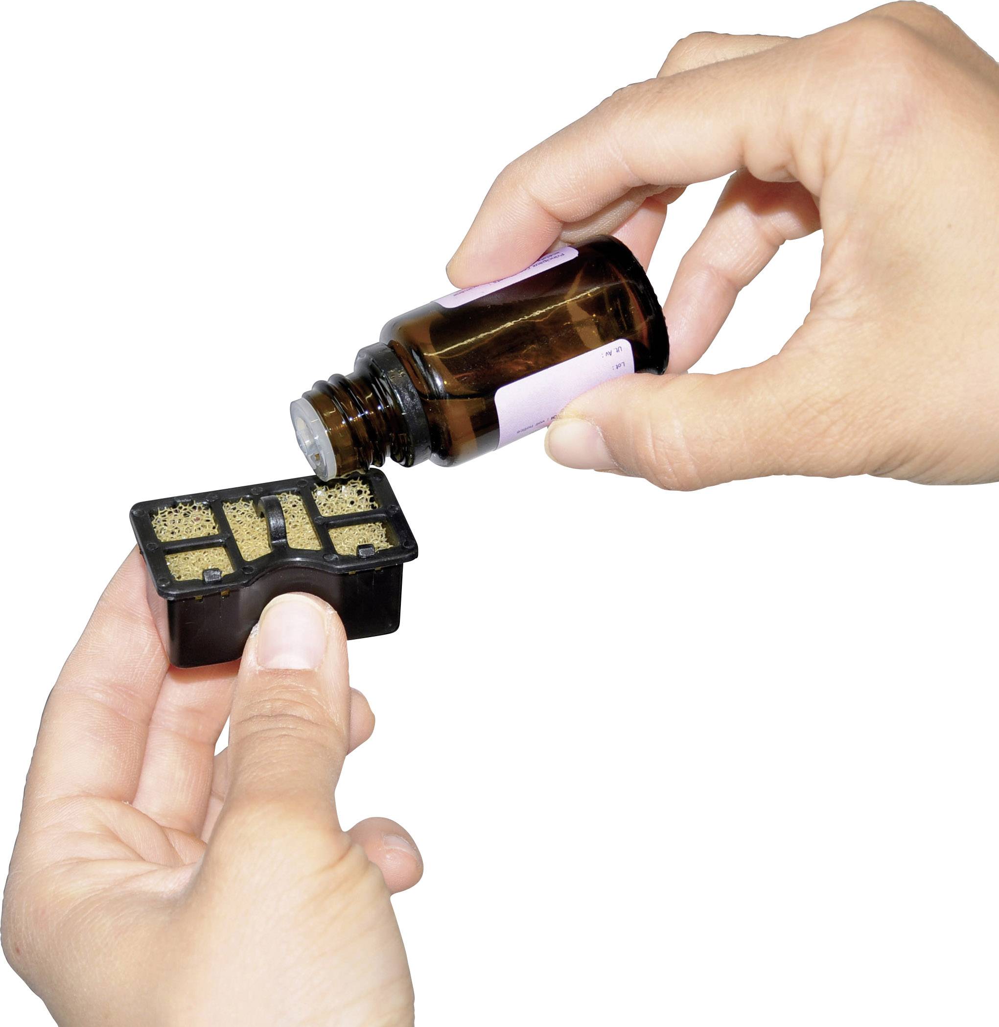 Two hands are holding a small bottle and a rectangular container. Liquid is being carefully poured from the bottle into the container.