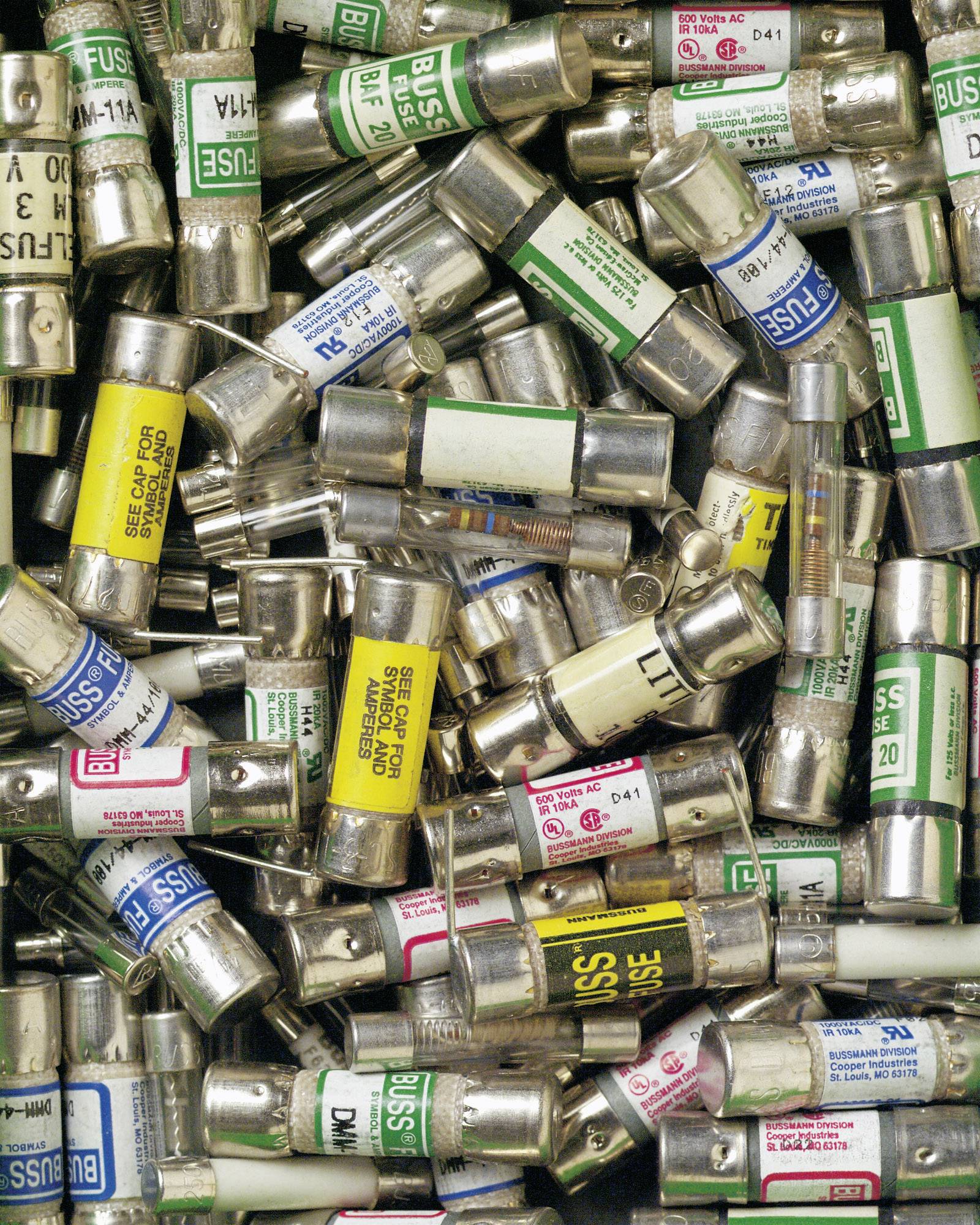 A collection of various fuses with colourful labels, stacked haphazardly on top of each other.