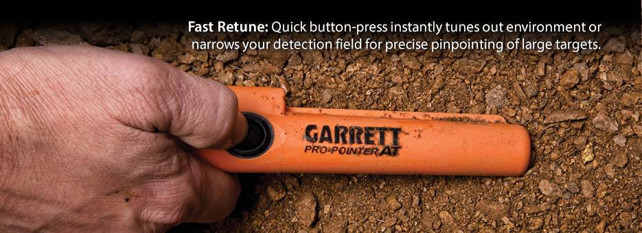 A hand holds an orange GARRETT PRO-POINTER AT detector over soil. Above it reads: 'Fast Retune' with an explanation of the function.