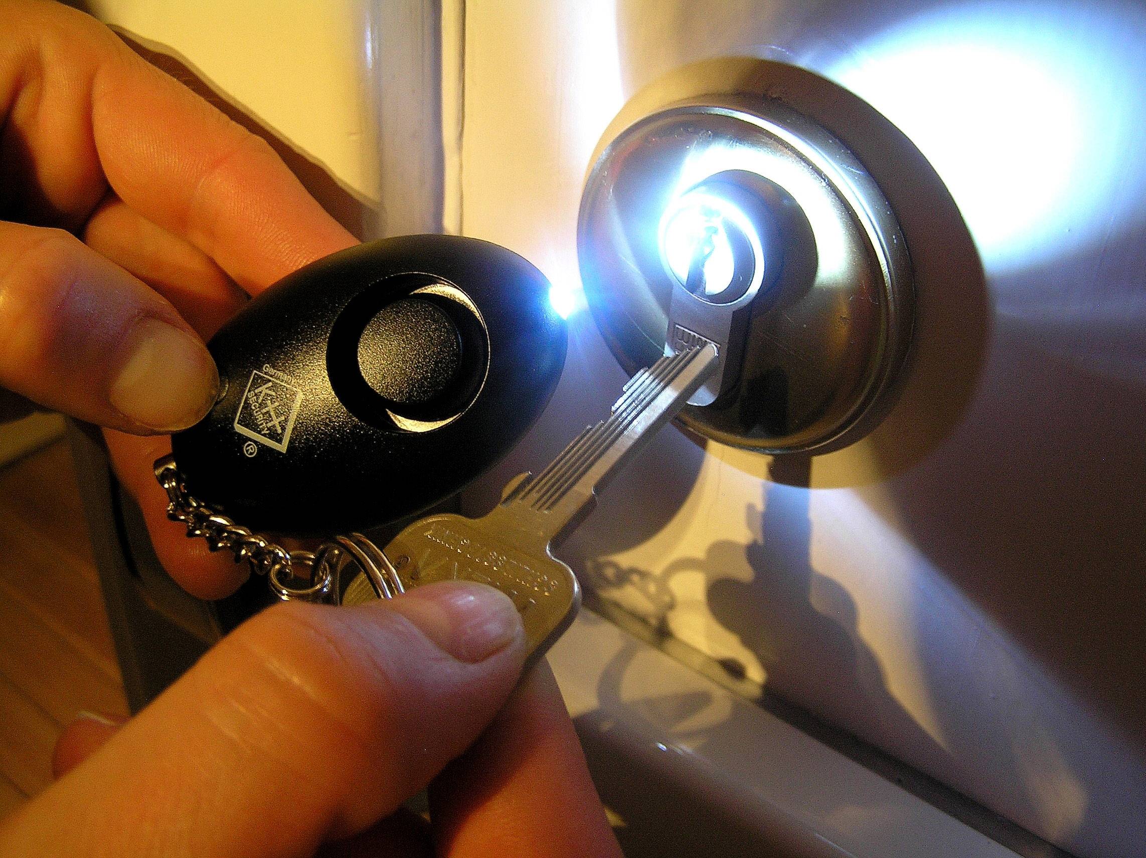A hand is holding a key with a torch to unlock a lock in the dark.Note: In British English, 