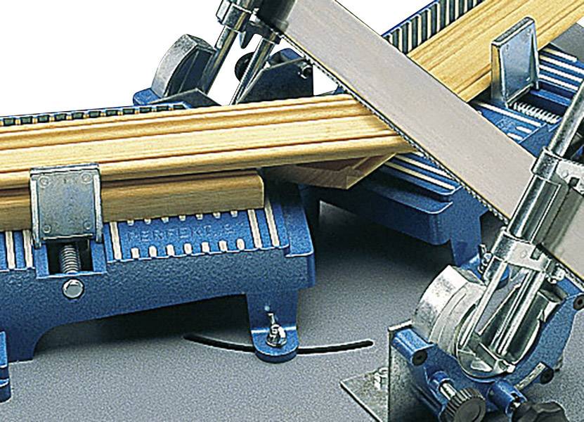 A blue mitre saw is currently cutting a bundle of wooden battens. The saw blade is slightly angled, and the machine looks industrial.