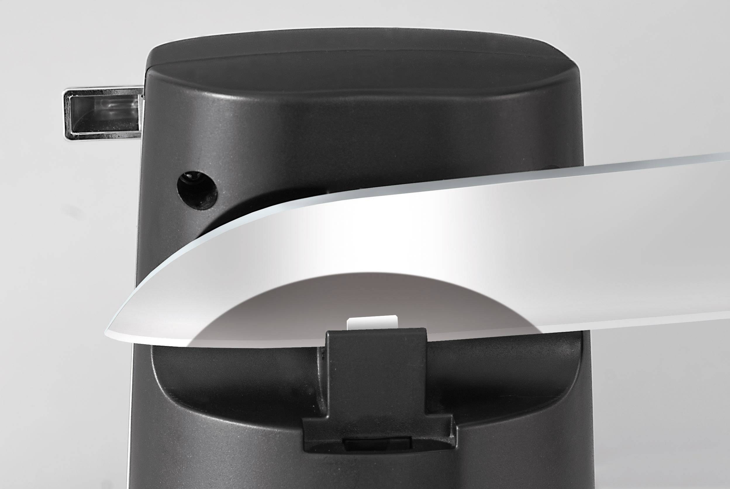 An electric knife sharpener with a knife being guided through the sharpening mechanism to hone the blade.