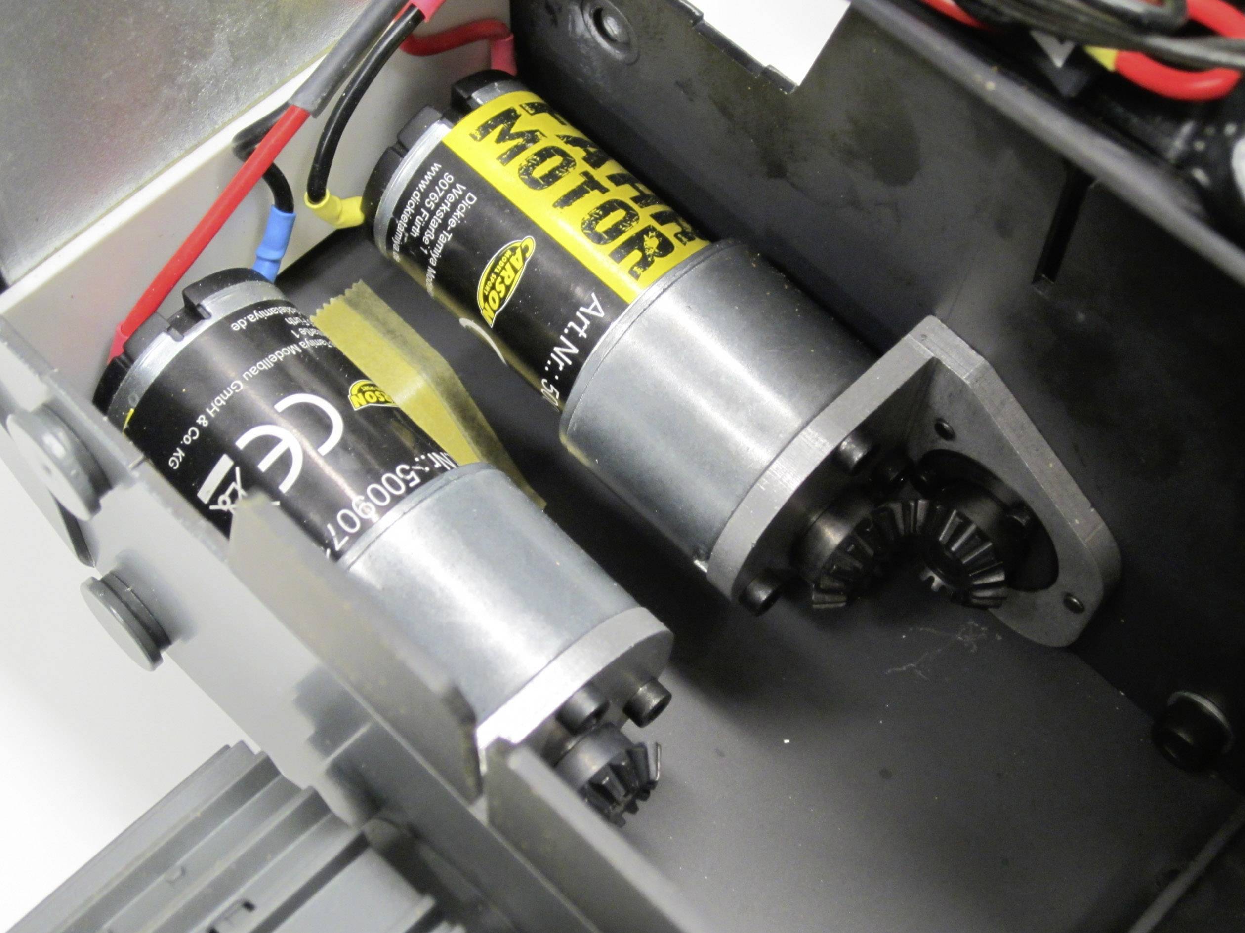 In the image, two electric motors with cable connections are visible within a device. One of the motors bears the label 'MOTOR'.
