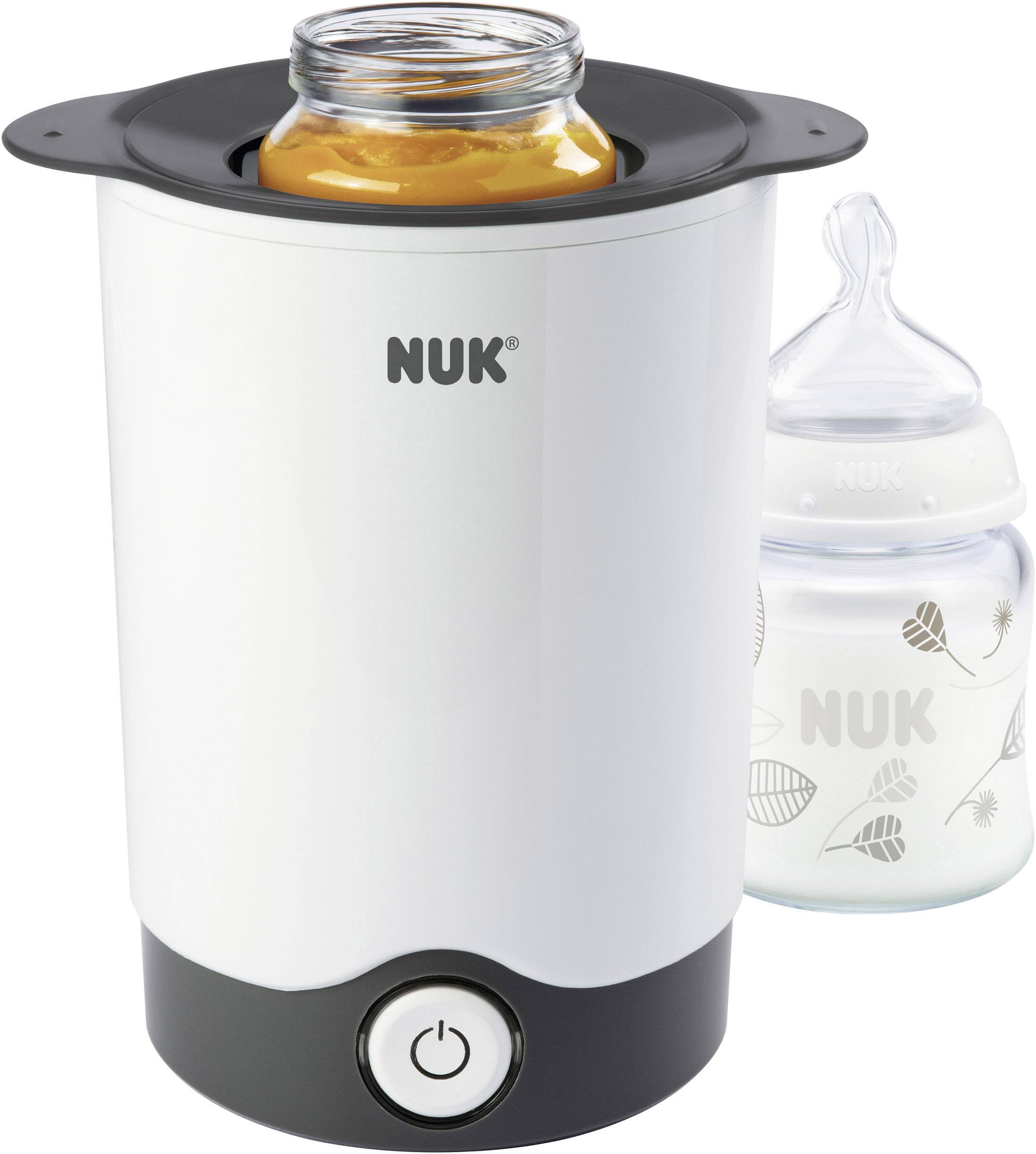 A bottle warmer with a glass container full of baby food inside the device, with a filled baby bottle with a teat placed beside it.