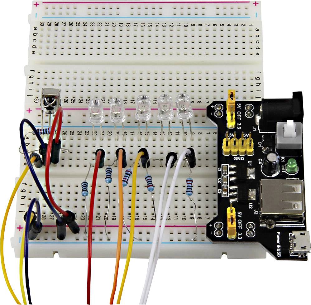 A breadboard with multiple LEDs, resistors, and jumper cables. A microcontroller is connected on the right.