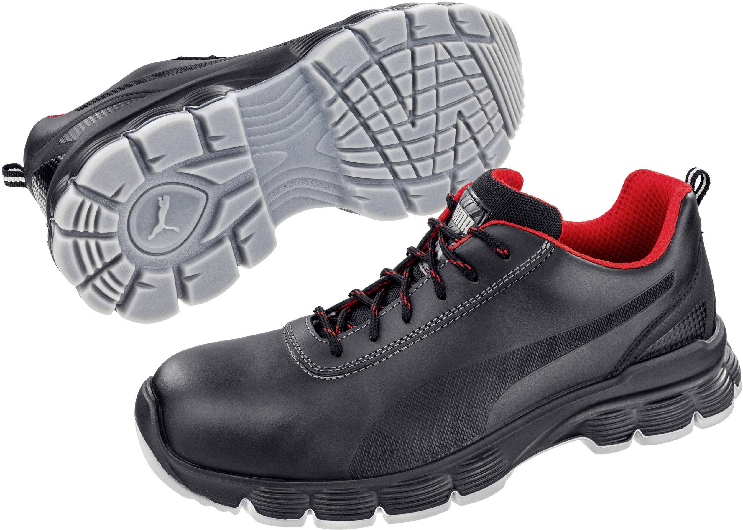 Two black sports trainers with red accents and robust soles. One shows the upper side, the other the tread sole.