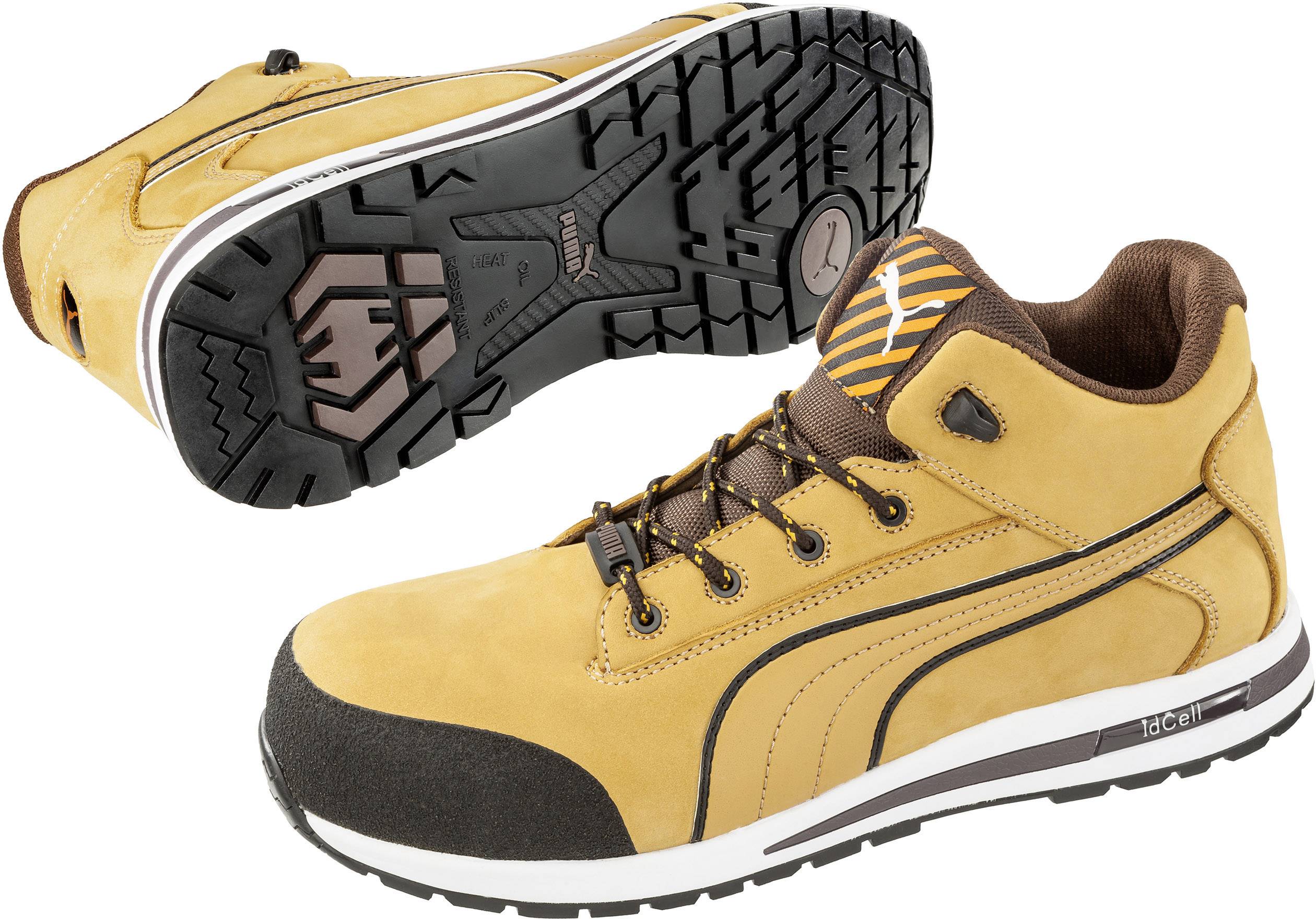 A pair of yellow work boots with protective toe caps, black soles, and brown laces. In the background, the sole of a boot is visible.