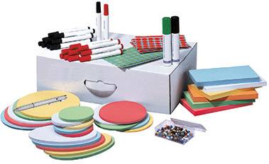 A box full of office and stationery supplies, including coloured sticky notes, pens, and drawing pins, arranged on a table.