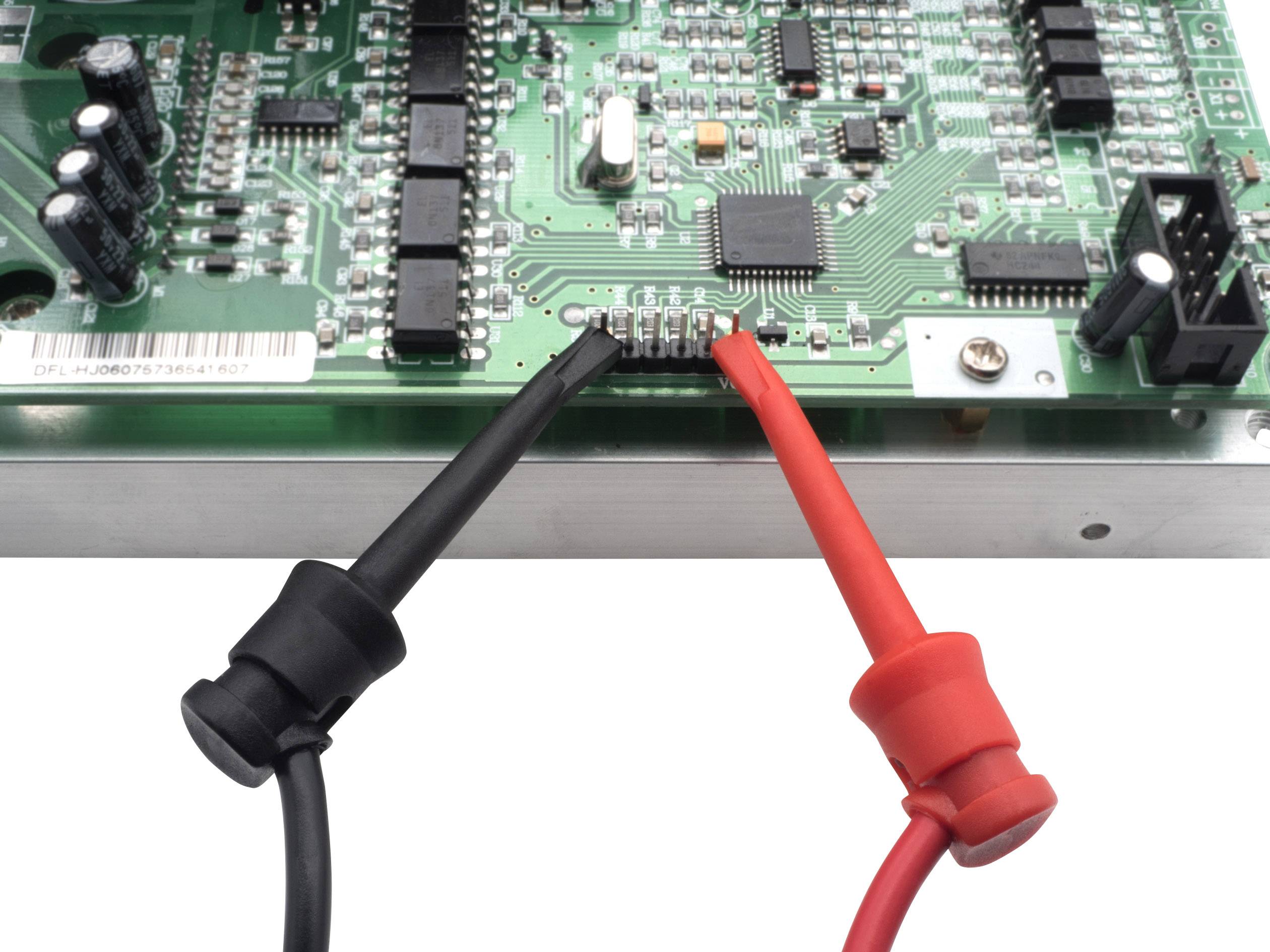 A circuit with two probes, one black and one red, connected to different points on the circuit board.
