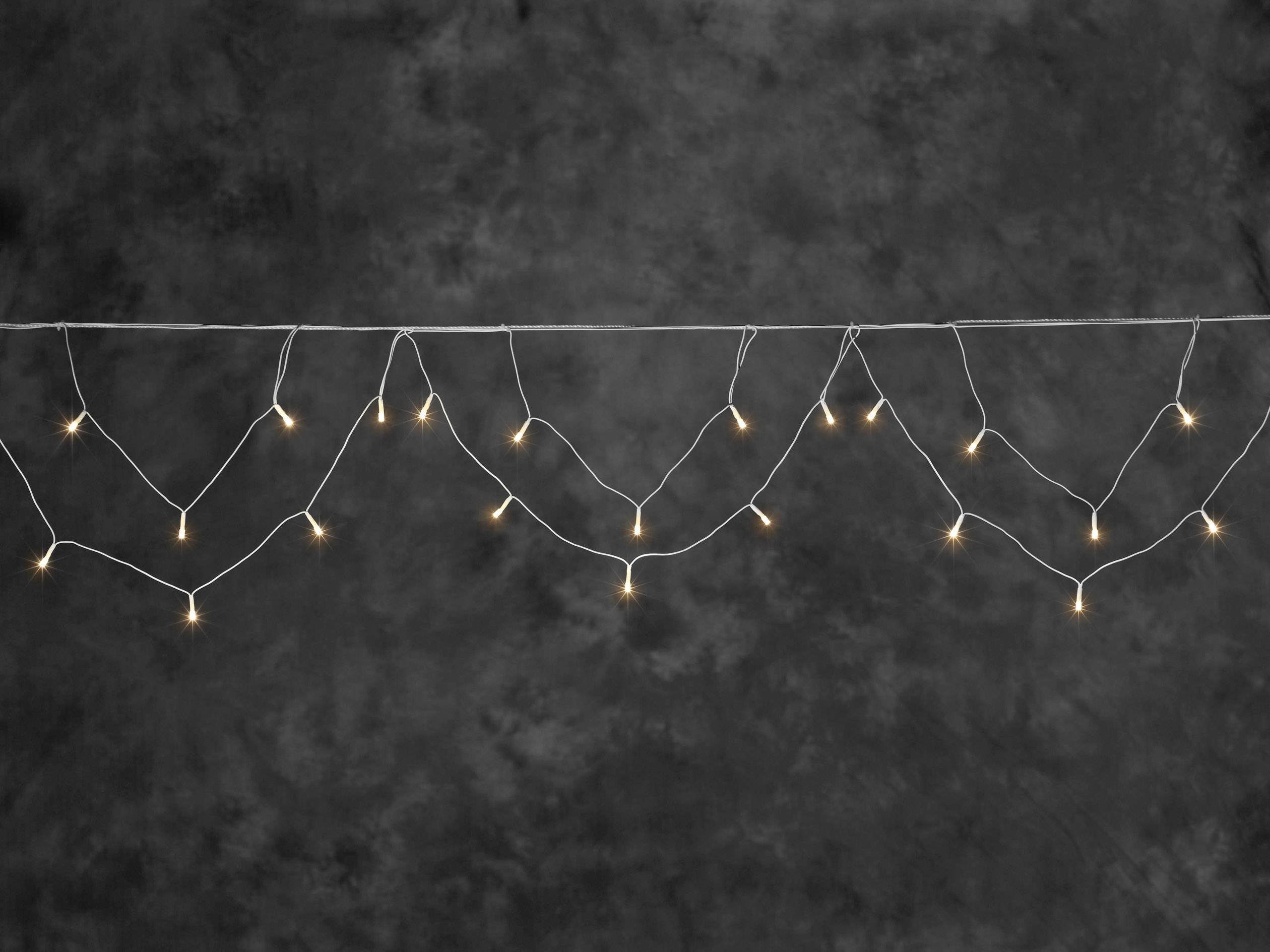 String of warm white fairy lights hung in graceful arches against a dark background.